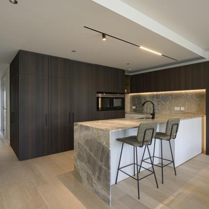 Leefkeuken in natuursteen met warme accenten en toegang tot de berging via de kastenwand - deel 01 Leefkeuken in natuursteen met warme accenten en toegang tot de berging via de kastenwand - deel 01