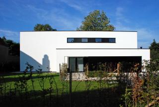 Voorgevel villa met eenvoudig volumespel in witte crepi Voorgevel villa met eenvoudig volumespel in witte crepi